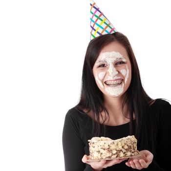 Funny portrait of beautiful young caucasian woman with birthday cake on her face, isolated on white background