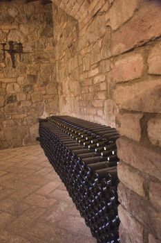 Wine bottles stacked aging along a wall in the winery