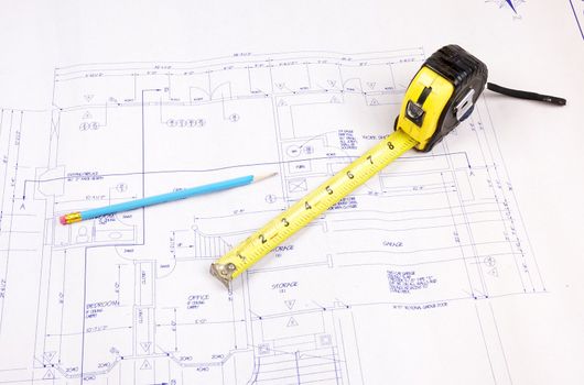 Set of building plans for a custom house with tape measure and pencil