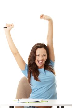 Yound student woman with hands raised and big smile, sitting behind the desk. Isolated on white