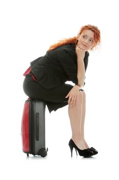 Young redhead businesswoman (deaf with hearing aid) with red suitcase, isolated on white background