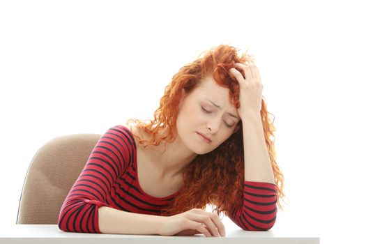 Sad business woman sitting behind the desk, isolated on white
