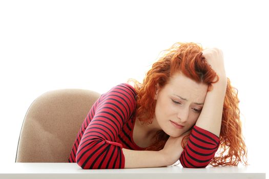Sad business woman sitting behind the desk, isolated on white