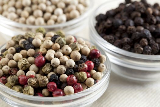 Glass bowl of mixed dried peppercorns.