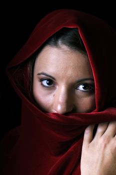 Beautiful young brunette woman in closeup with red shawl over face