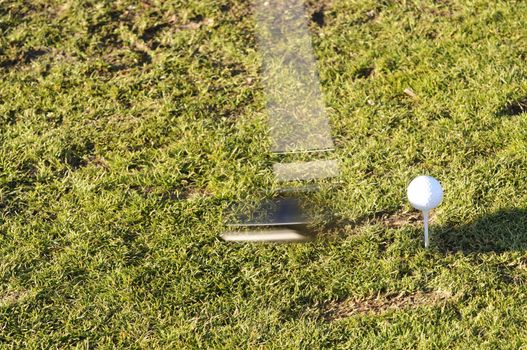 golf club mid swing about to strike the ball