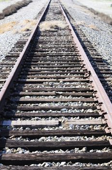 Railway line overgrown with weeds and broken ties leading off into the distance
