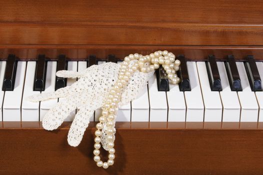 Lace glove and pearls sitting on piano keys