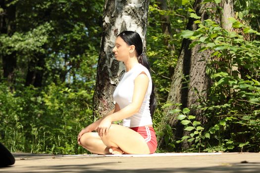 Young girl in lotus pose in the park