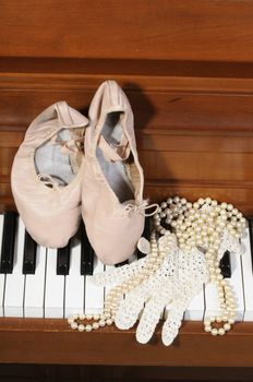 ballet shoes, lace glove and pearls on a piano keys