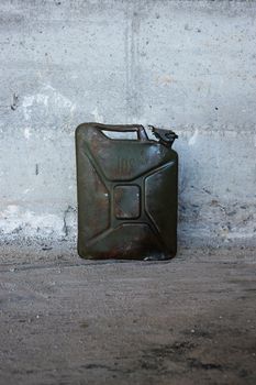 a green jerry can on concrete floer.