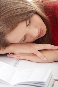 Teenage girl studying at the desk being tired, isolated on white