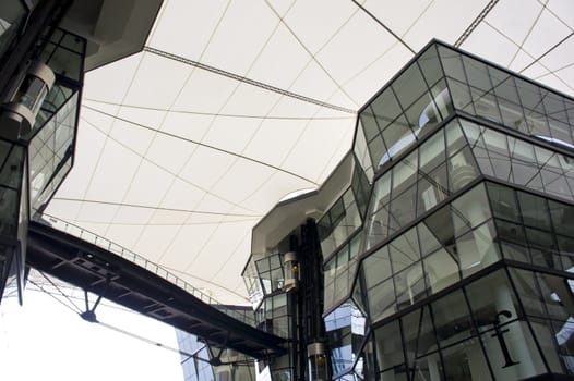 Futuristic Angular green glass building structure connected by aero bridge with white canvas canopy