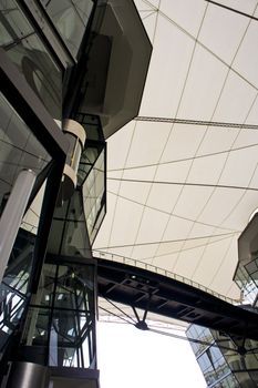 Futuristic Angular green glass building structure connected by aero bridge with white canvas canopy