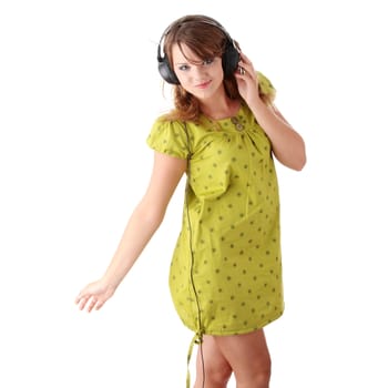 Beautiful teenage girl in a green dress listening to music with big headphones, isolated on white