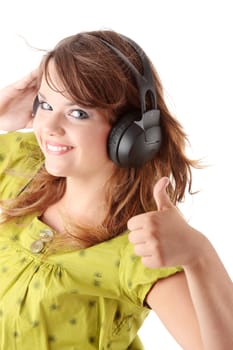 Beautiful teenage girl in a green dress listening to music with big headphones, isolated on white