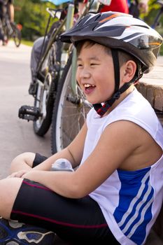 Young Asian boy resting after cycling.