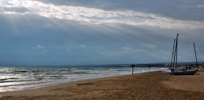 Beach with boats on sand and dramatic sky