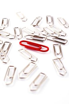 Red paper clip among rows of metal paper clips