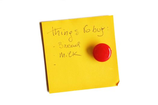 Yellow post-it isolated on white with round red magnet and handwritten message