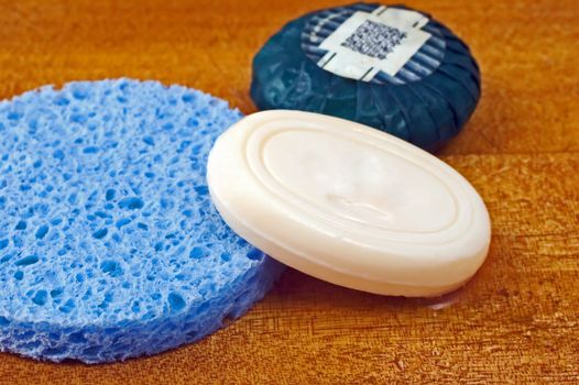 Soaps and blue sponge on wooden surface