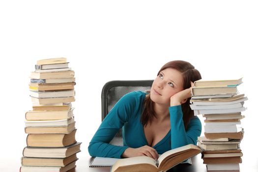 Teen girl learning at the desk with lot of books, isolated on white