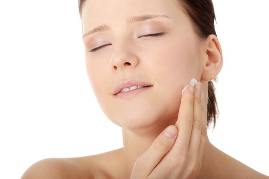 Woman applying moisturizer cream on face. Close-up fresh woman face.