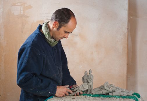 Artist in studio finishing several small resin statues