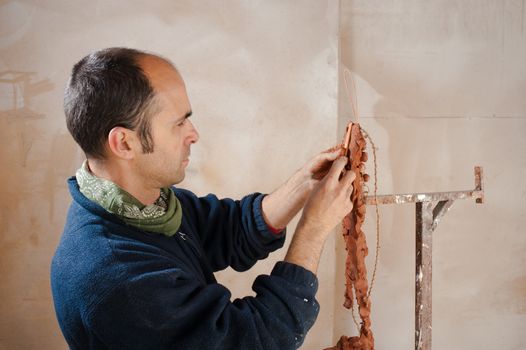 Artist in his studio working on a clay statue