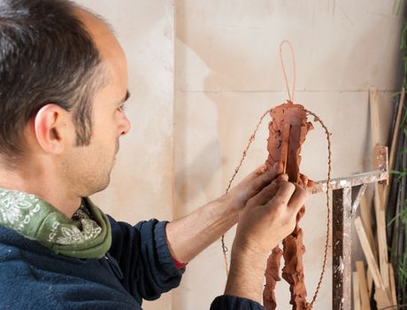 Artist in his studio working on a clay statue