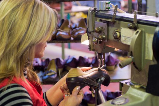 Experienced worker sewing leather shoes in a production line