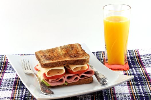 toasted bread, cheese, tomatoes and sausage on a plate and a glass of orange juice