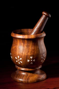 Wooden mortar and pestle on dark wood background