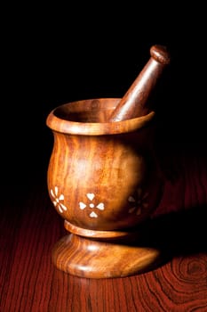 Wooden mortar and pestle on dark wood background