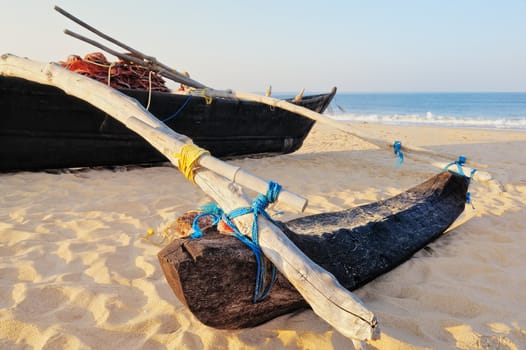 Old boat with fishing net on sandy shore. In Goa