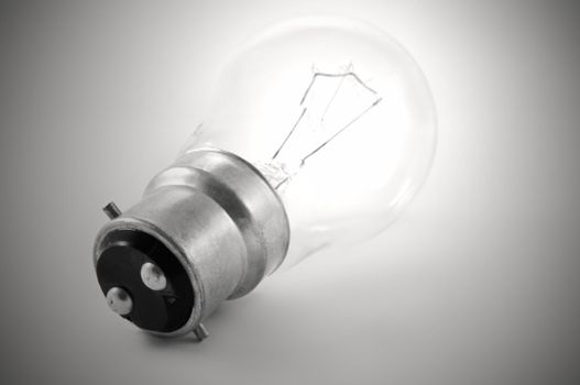 Close up of a single illuminated light bulb with grey background
