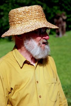 Old man with grey beard and glasses wearing shirt in village