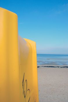 Big yellow dustbin in background of blue still sea and sky