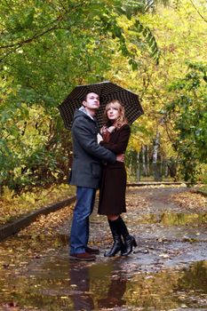 Couple in autumn park under a umbrella