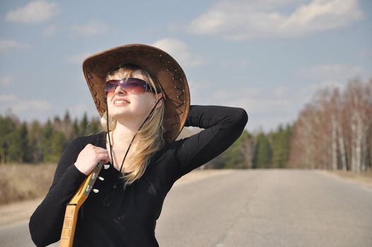 The beautiful blonde with a guitar on the road