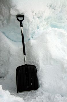 A black snow shovel in the snow