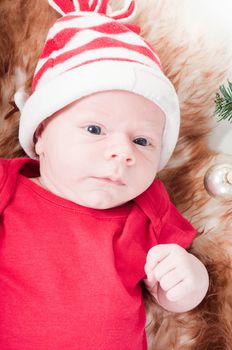 Newborn baby in chritstmas hat lies on fur