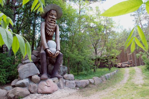 Wooden man, demon or devil carrying stone. european myths.