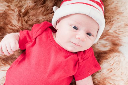 Newborn baby in chritstmas hat lies on fur