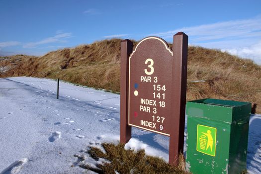 third tee information sign on a snow covered links golf course in ireland in snowy winter weather