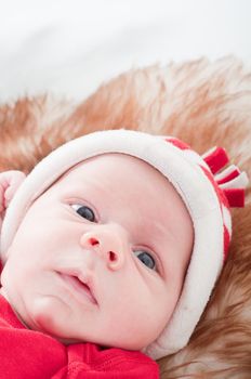 Newborn baby in chritstmas hat lies on fur