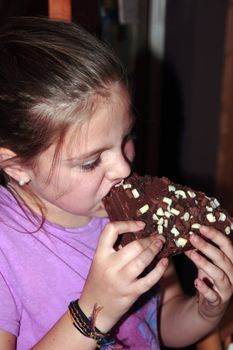 young girl enjoying a taste of chocolate cake