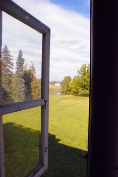 Window to the autumn manor park and the pond