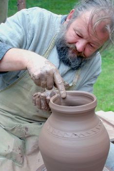 Ancient crafts - pottery fair - master completes clay jar