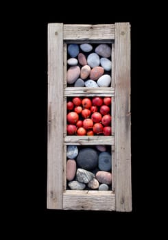 An old window frame with sea stones and little red apples in it.